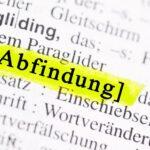 Das Wort Abfindung in einem Wörterbuch, hervorgehoben mit einem gelben Marker. Abfindungen bei betriebsbedingter Kündigung verständlich erklärt.